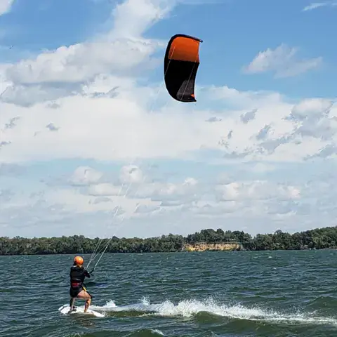 Élève en kitesurf sur un lac, tracté par son aile
