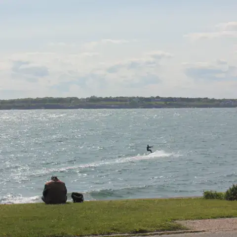 Kitesurfeur sur l'eau, aile jaune dans le ciel, vue depuis la rive
