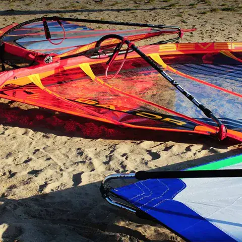 Voiles de windsurf posées sur le sable