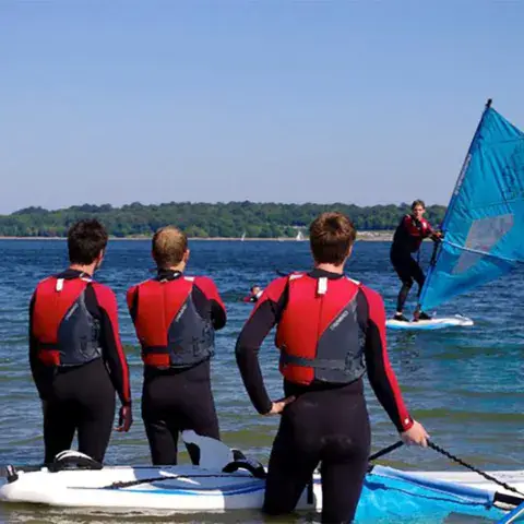 Groupe en combinaison à la mise à l'eau d'un cours de windsurf