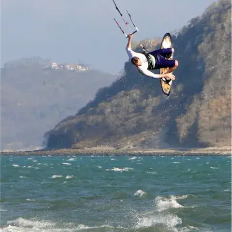 Saut d'un kitesurfeur devant une côte