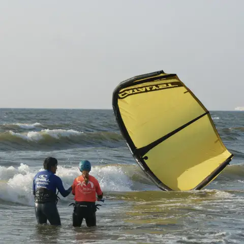 Moniteur et élève qui récupèrent une kite jaune dans l'eau