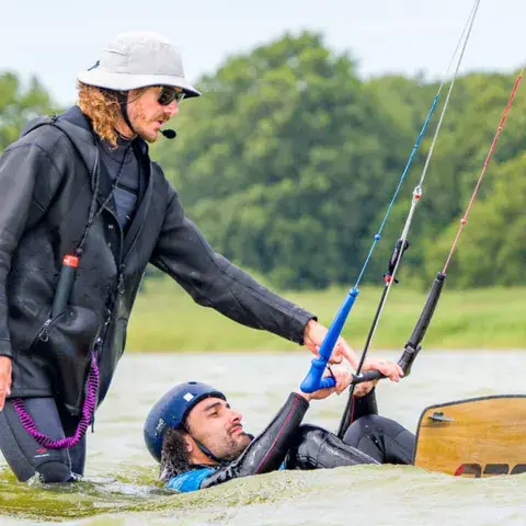 Le moniteur aide un élève dans l'eau, avec casque de communication