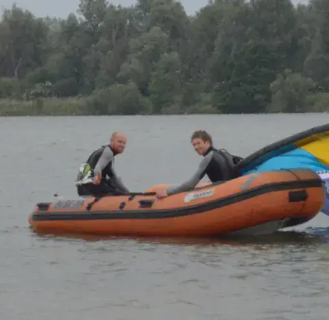 Moniteurs dans un bateau pneumatique près d'un kite
