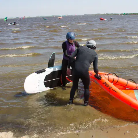 Un moniteur aide un élève au bord de l'eau