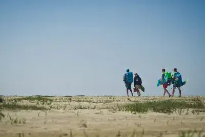 Groupe marchant sur la plage avec kites et planches