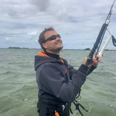 Un kitesurfeur tient sa barre dans l'eau
