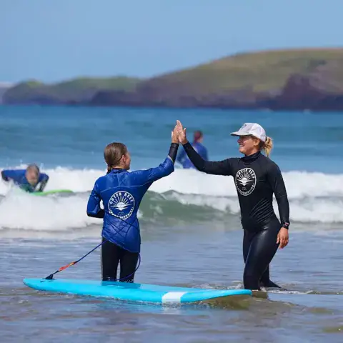 Une monitrice félicite une élève pendant un cours de surf