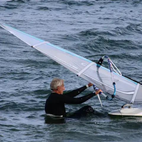 Windsurfeur relevant sa voile dans l'eau