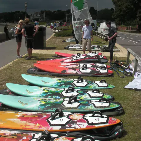 Planches de windsurf alignées sur l'herbe lors d'une journée de démo