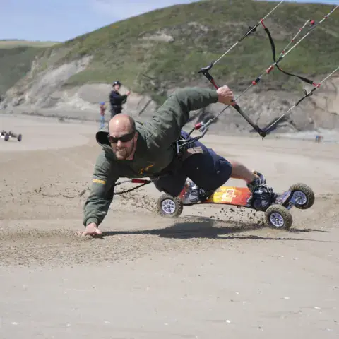 Pratiquant de kite landboard sur la plage