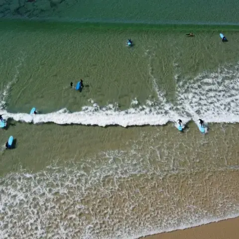 Groupe de surfeurs dans le shore break, vue aérienne