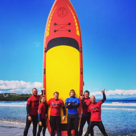 Équipe devant un grand paddle collectif sur la plage