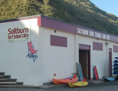 Local de l'école au pied de la colline, avec planches et combinaisons