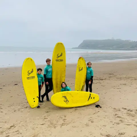 Moniteurs et planches de surf jaunes plantées dans le sable