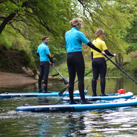 Cours de paddle sur la rivière, entre les arbres