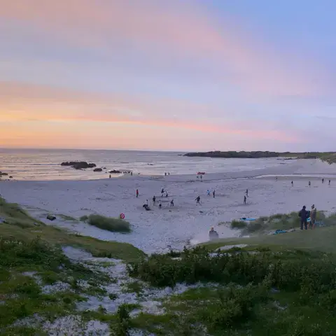 La plage au coucher du soleil, avec des baigneurs