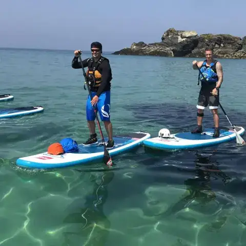 Groupe de paddle sur une eau claire, près de la côte