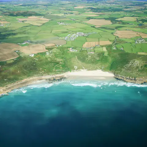 Vue aérienne d'une plage de sable bordée de falaises et de champs