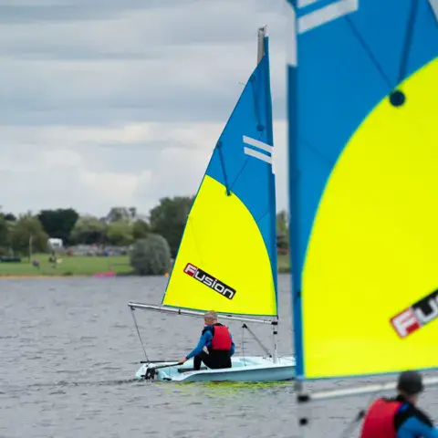 Dériveur à voiles jaune et bleue sur le plan d'eau