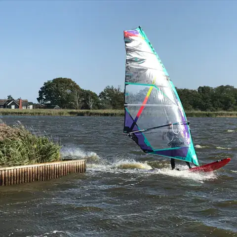Windsurfeur sur le plan d'eau, rives plantées de roseaux
