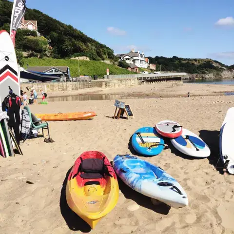 Kayaks et stand up paddles posés sur le sable