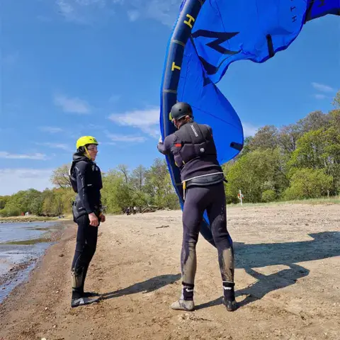 Moniteur et élève avec un kite sur la plage