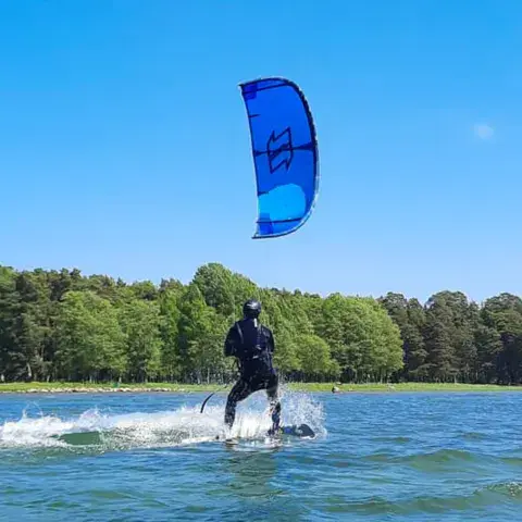 Kitesurfeur sur l'eau devant une rive boisée