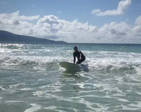 Un surfeur dans l'eau peu profonde, montagnes en arrière-plan