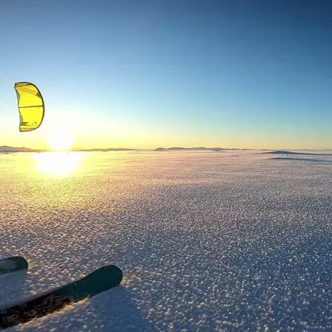 Kite et skis sur la neige au coucher du soleil