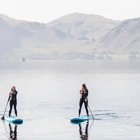 Un groupe en paddle sur le lac, montagnes en arrière-plan