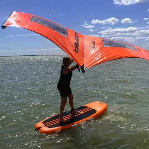 Rider de wing surf debout sur sa planche orange