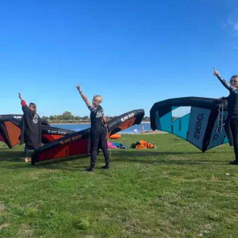 Groupe de riders bras levés devant des ailes posées sur l'herbe