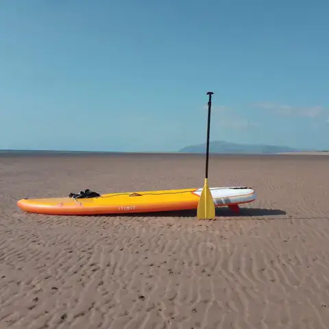 Un pratiquant de stand up paddle au crépuscule