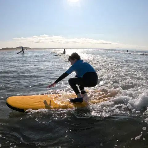 Élève de surf accroupi sur une planche jaune