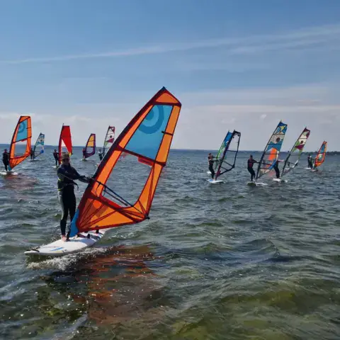 Groupe d'élèves de windsurf sur l'eau