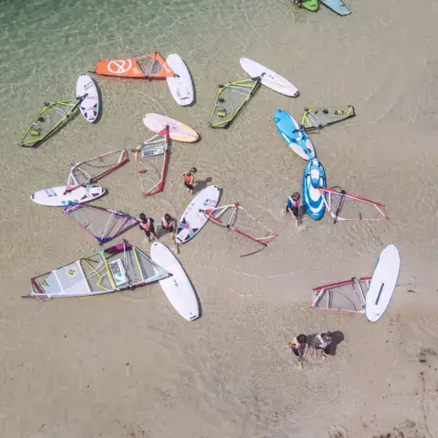 Planches et voiles posées sur la plage, vues du ciel