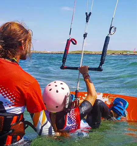 Un élève de kitesurf encadré par un moniteur dans l'eau