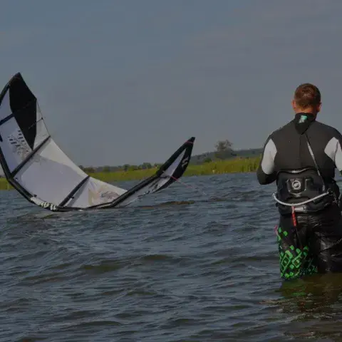 Deux élèves dans l'eau, aile de kite étalée devant eux