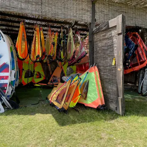 Voiles et planches rangées dans la remise de la base