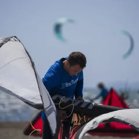 Un moniteur prépare une aile sur la plage