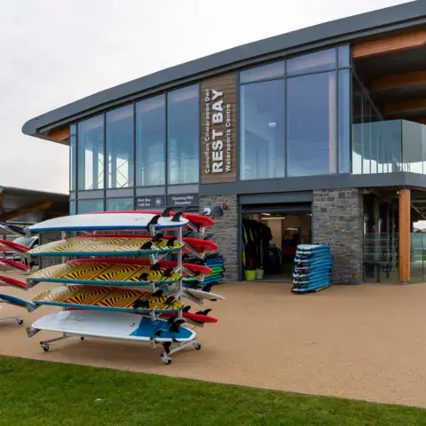 Le bâtiment du Rest Bay Watersports Centre et ses râteliers de planches