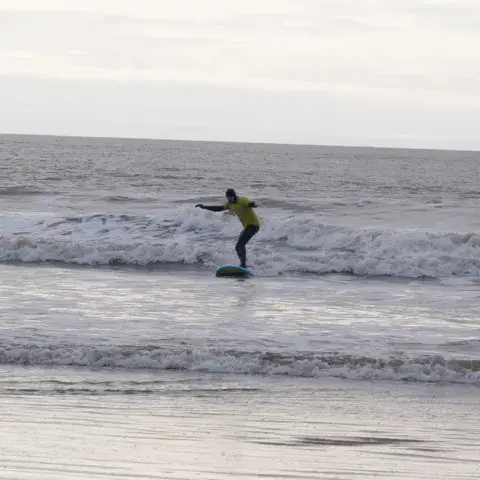 Un surfeur debout sur sa planche dans les vagues