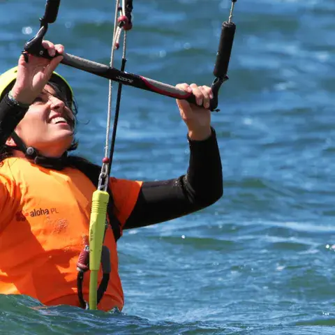 Élève de kitesurf dans l'eau, barre en mains