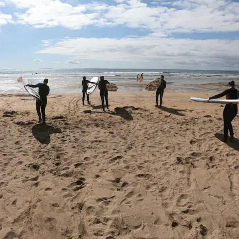 Groupe d'élèves avec leurs planches sur la plage