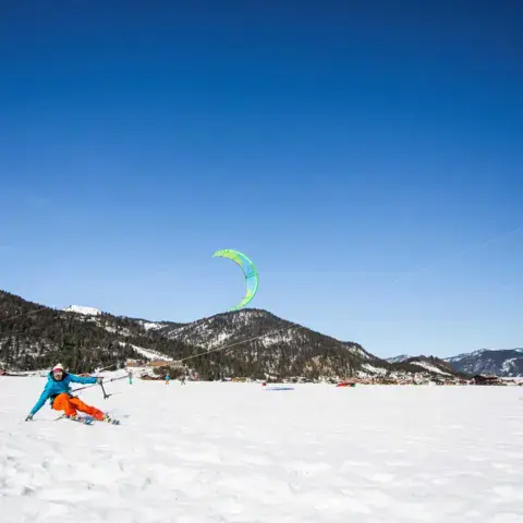Un snowkiteur sur la neige, sous un ciel bleu