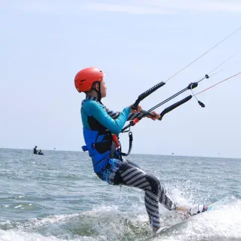 Jeune kitesurfeur avec casque en pleine session