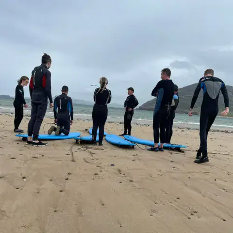 Un groupe en combinaison sur la plage avec des planches de surf