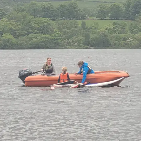 Un bateau de sécurité et un windsurfeur sur le loch