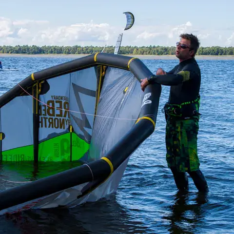 Moniteur tenant une aile dans l'eau peu profonde du lac